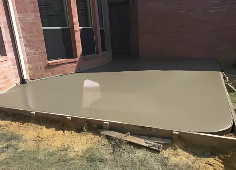 Freshly poured smooth concrete patio slab against a brick wall with forms, Bayonet Point, FL